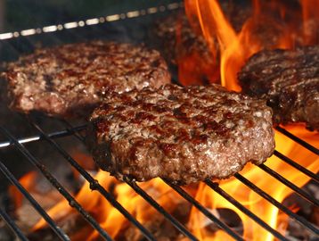 Juicy beef patties grilling over open flames.