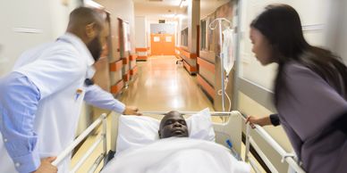 Doctors rushing a patient on a hospital bed through a corridor.