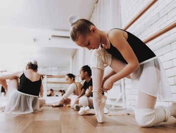 Young ballerinas preparing for ballet class in a studio.