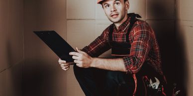 A young worker with a clipboard in a warehouse setting.