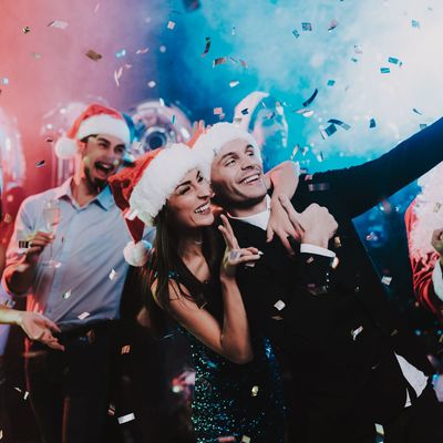 Group celebrating Christmas with Santa hats and confetti.