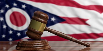 Wooden judge's gavel with Ohio state flag in the background.