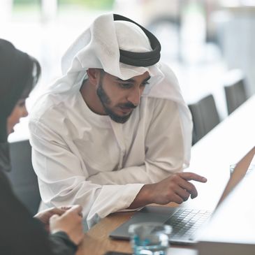 Man in traditional Middle Eastern attire working on a laptop.