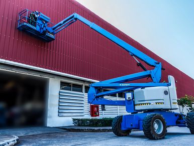 Blue boom lift working on red building.