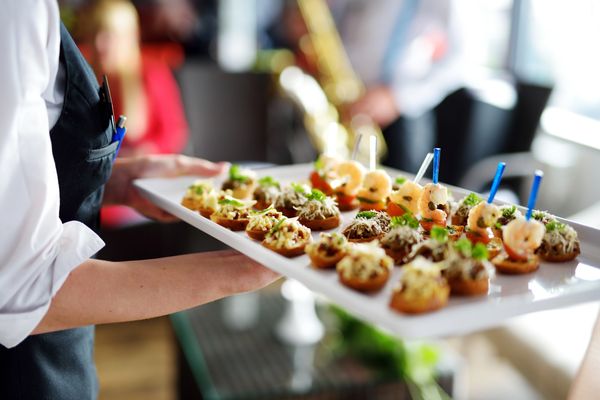 Pure Catering server carrying a tray of canapes at a Toronto event