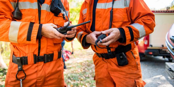 Two people in orange safety uniforms holding walkie-talkies.