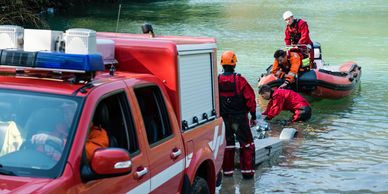 Rescue team conducting water rescue operation with boat and emergency vehicle.