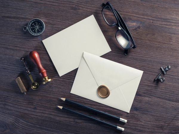 Vintage stationery with envelope, glasses, compass, and pencils.