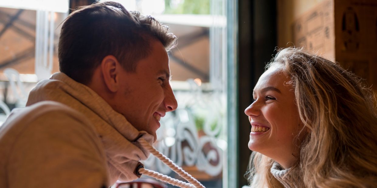 Couple sharing a joyful moment and smiling at each other indoors.