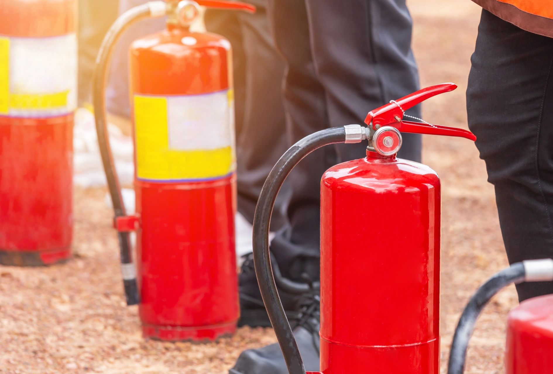 Close-up of red fire extinguishers with people in the background.