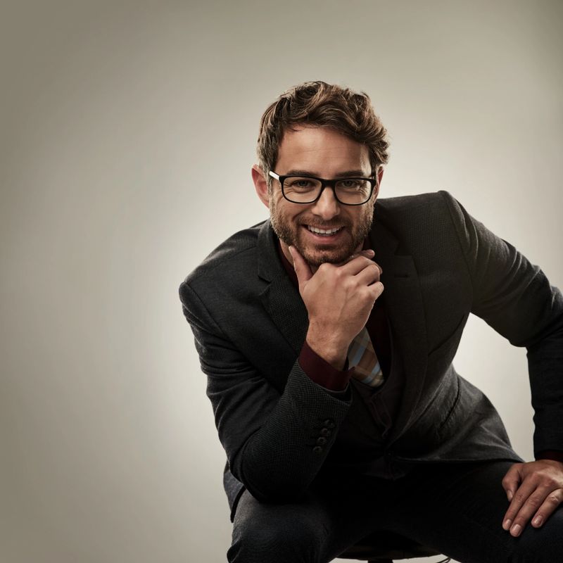 Studio portrait of a handsome young businessman looking thoughtful while sitting against a grey background