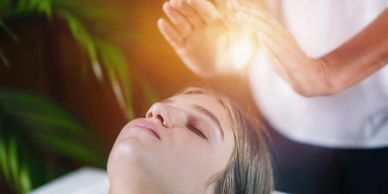 A person receiving energy healing therapy with hands glowing above the head.