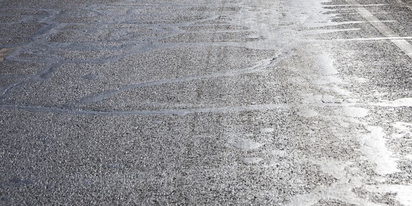 Close-up of a rough asphalt road surface with patch marks.
