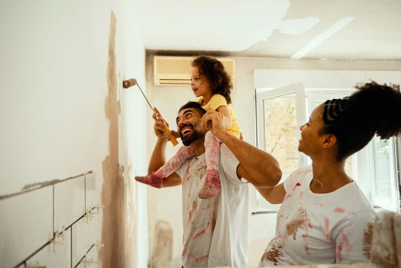 Young family renovating their home, painting wall
