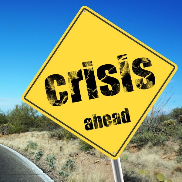 Yellow road sign saying 'crisis ahead'.