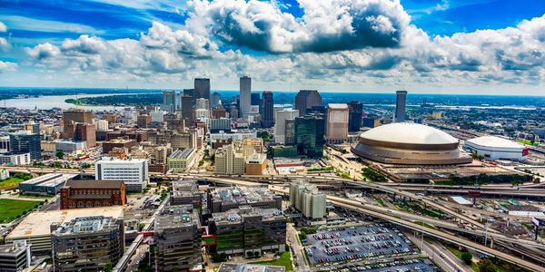 A vibrant city skyline with a large dome-shaped stadium under a bright blue sky.