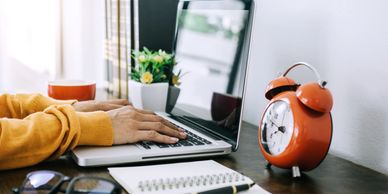 A person typing on a computer keyboard that is sitting on a desk.