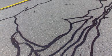 Black liquid spilled and spread on asphalt road.