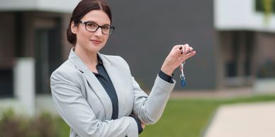Confident woman holding house keys outdoors, smiling.