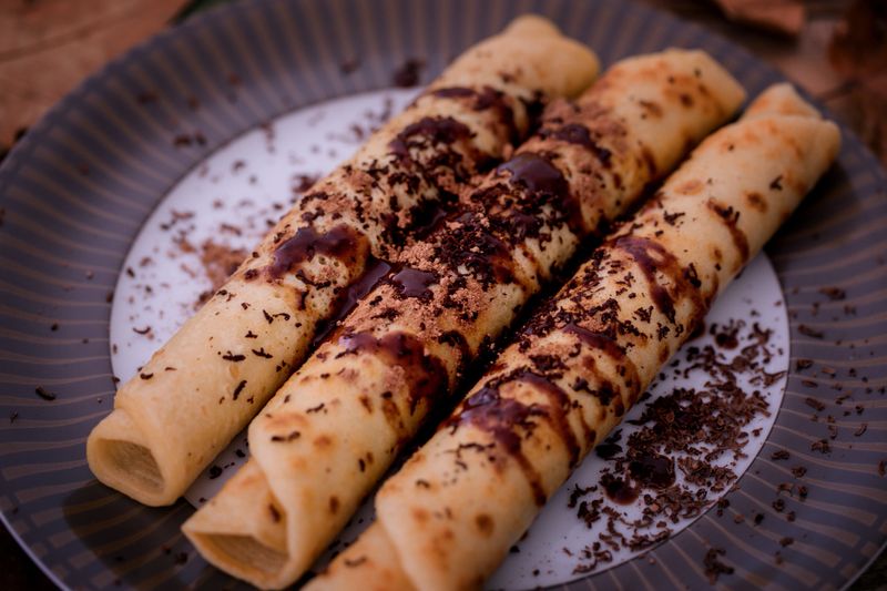 Crepes filled with chocolate spread, sprinkled with cocoa powder. Close-up, selective focus