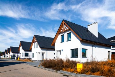 Modern white houses with black roofs under a blue sky.