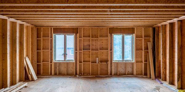 An unfinished wooden room under construction with two windows.