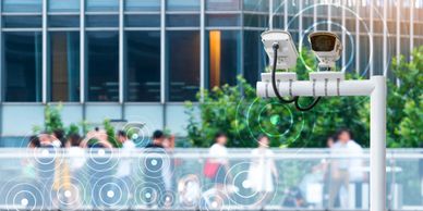 Security cameras monitoring a crowd outside a building with digital signal overlays.