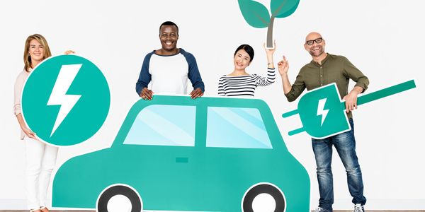 Four people hold eco-friendly electric car symbols.