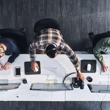 Three customer service agents working at desks with computers and headsets.