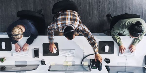 Three customer service agents working at desks with computers and headsets.