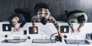 Three people working at computers in an office.