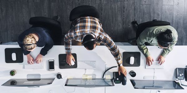 Overhead view of three call center agents working at their desks with headsets.