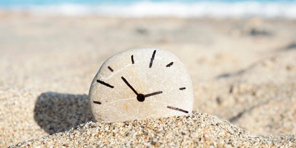 A small stone on the beach painted as a clock.