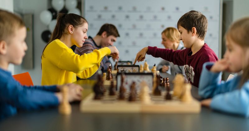 Kids of different ages, boys and girls, playing chess on the tournament in the chess club