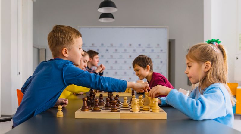 Kids of different ages, boys and girls, playing chess on the tournament in the chess club