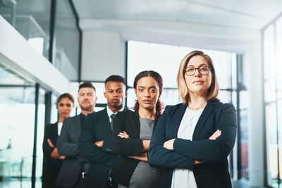 Confident diverse business team standing with arms crossed in modern office.