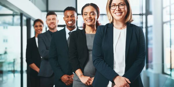 A diverse group of professionals standing in a modern office, smiling confidently.