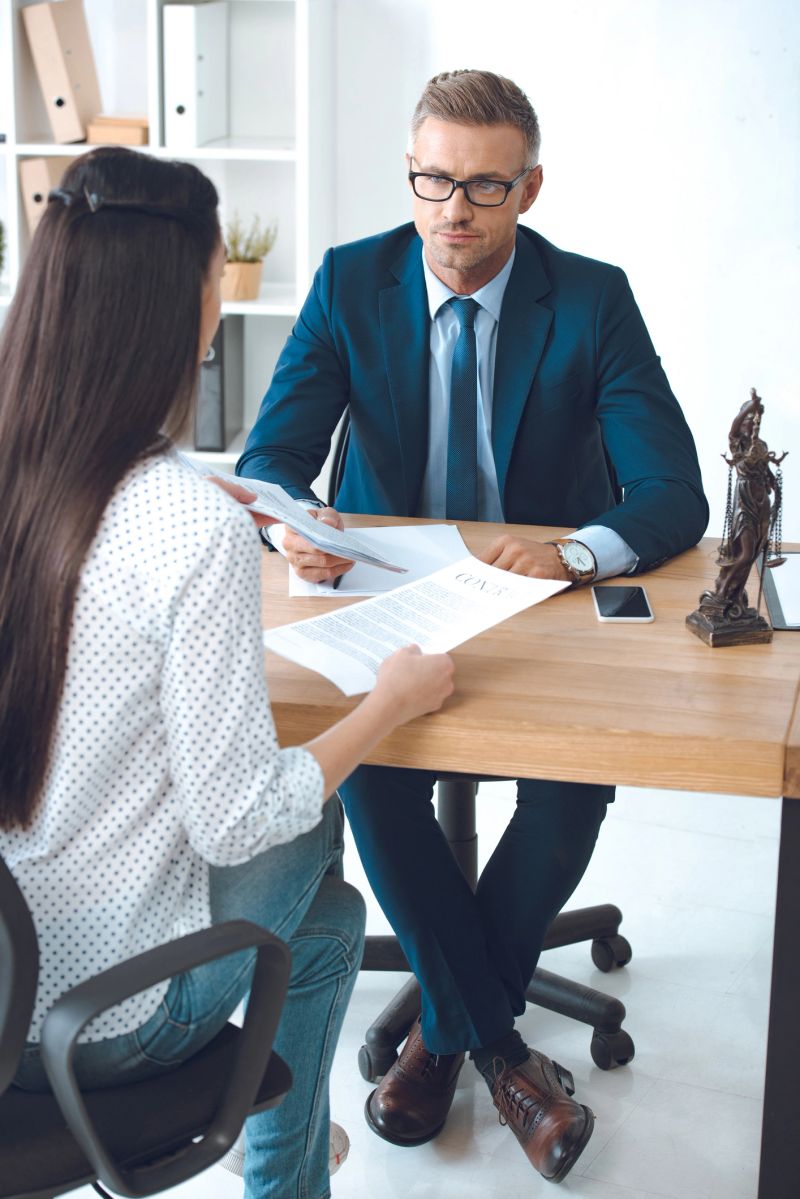 lawyer and client looking at each other while working with contract in office