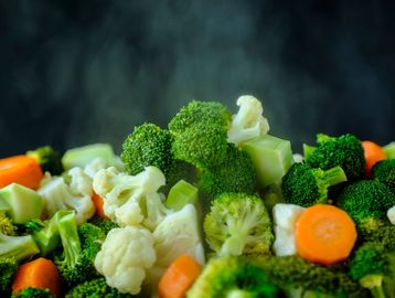 Steaming mixed vegetables including broccoli, cauliflower, and carrots.