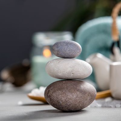 A stack of three smooth stones arranged in ascending size with a blurred candle in the background.