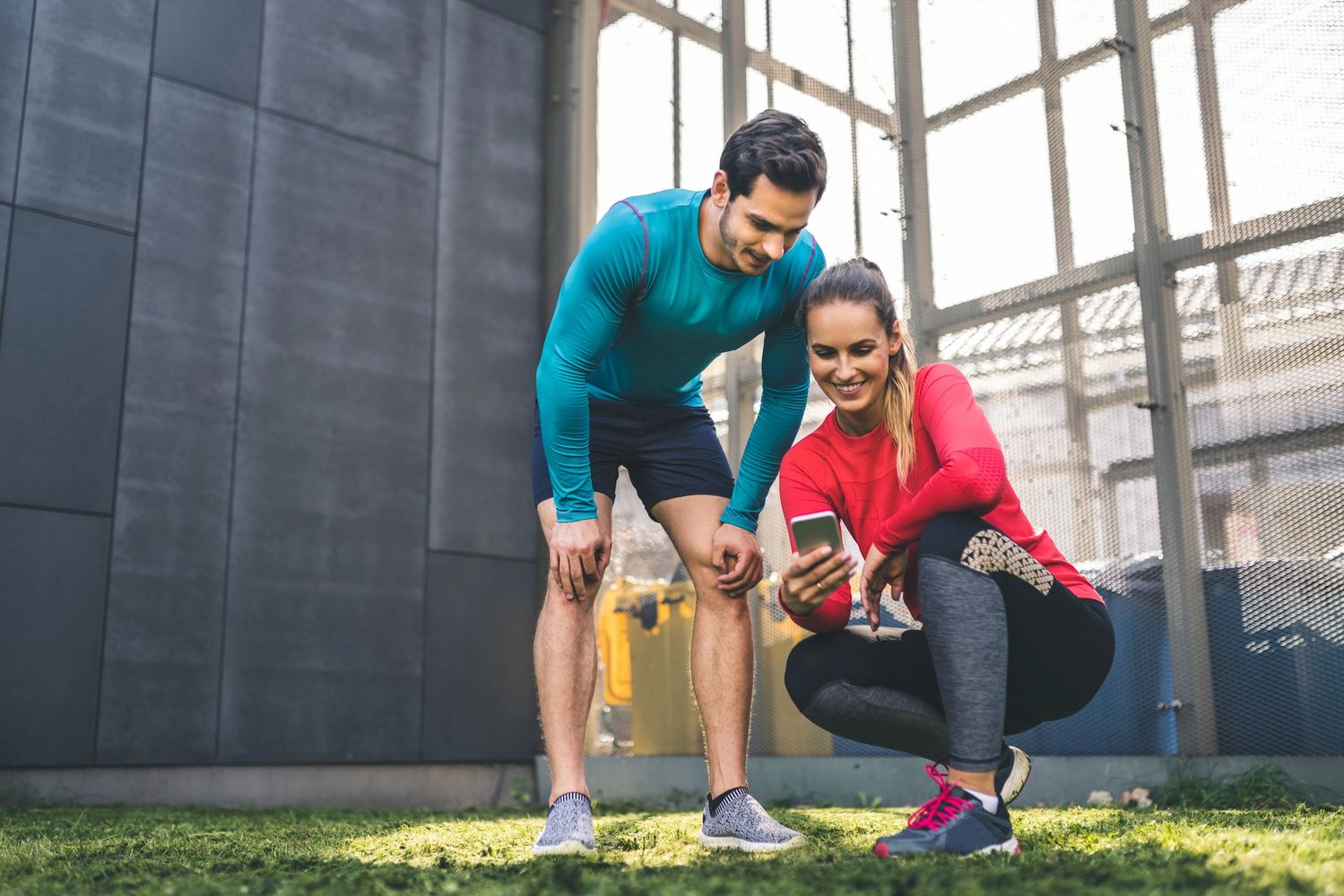 Two athletes checking their phone after a workout outdoors.