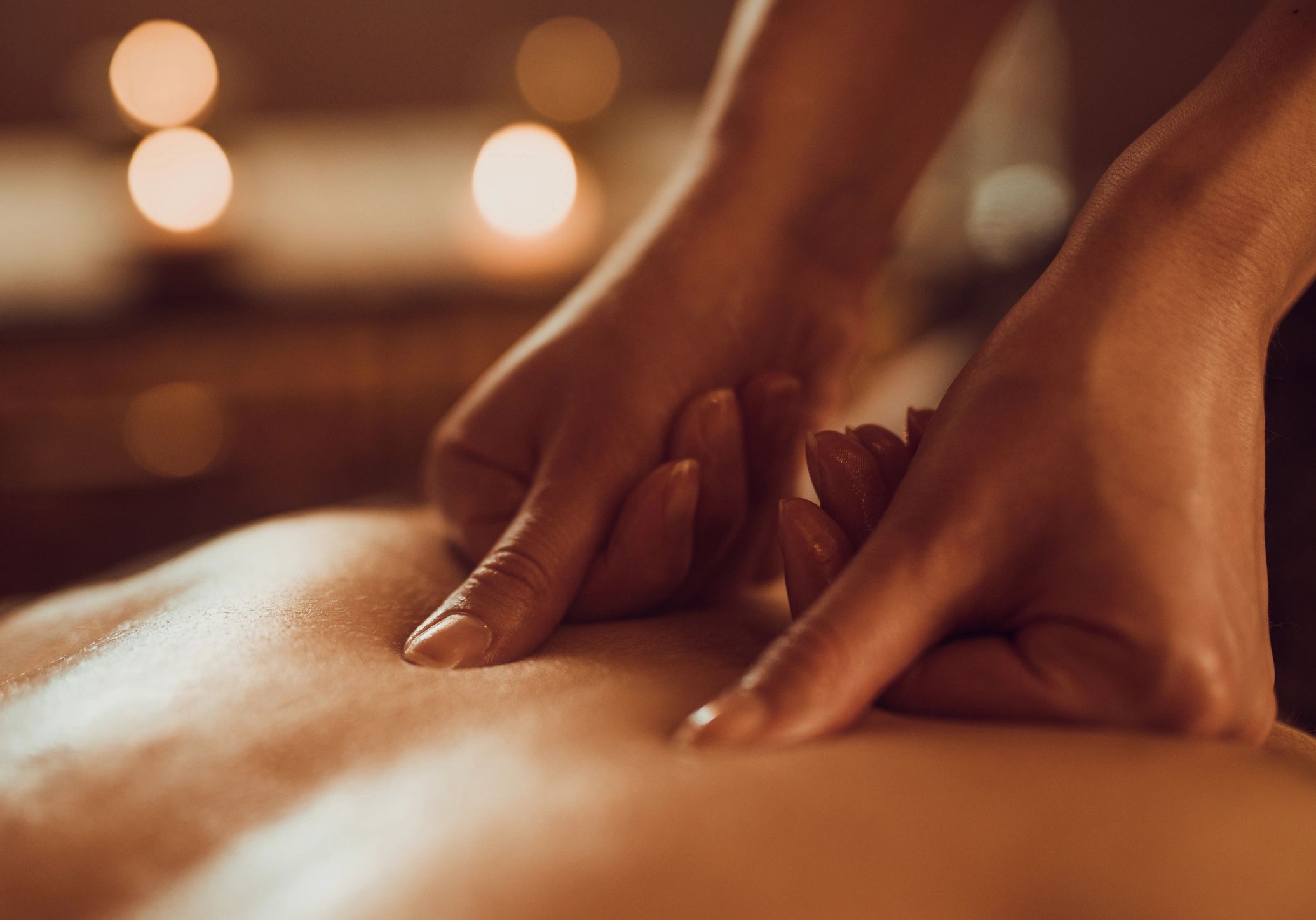 A woman receiving a relaxing shoulder massage with a purple flower in the foreground.