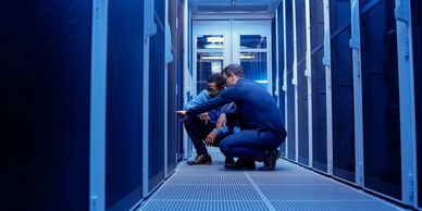 Two IT professionals working in a server room, inspecting equipment.
