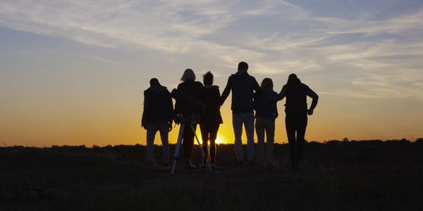 Group watching sunset with telescope.