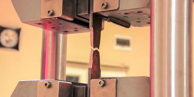 Close-up of a metal testing machine breaking a metal specimen.