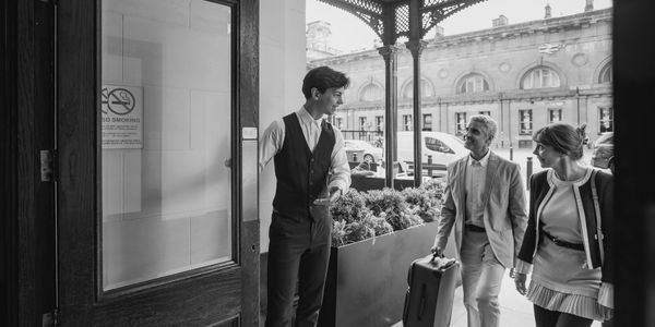 Hotel doorman welcoming guests with luggage on arrival.