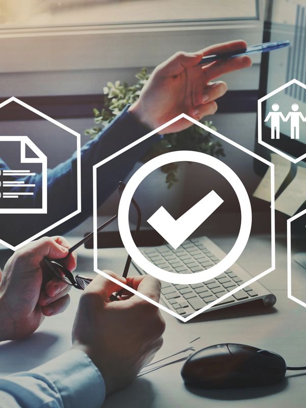 Two professionals discussing data and quality assurance on a computer.