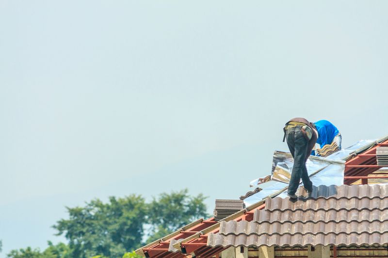 Construction roofer installing roof tiles at house building site