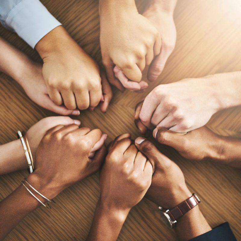 Closeup shot of a group of businesspeople sitting together at a table and holding hands