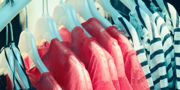 Red mesh and striped clothes hanging on white hangers in a closet.